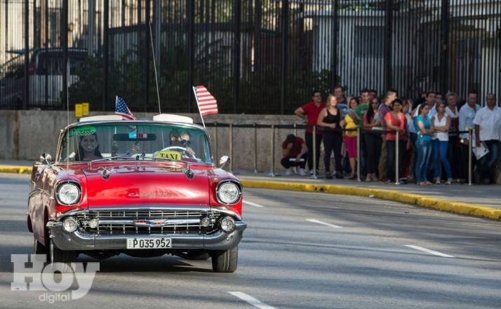 A vintage car with US flags drives by the US embassy in Havana, on July 20, 2015. The United States and Cuba formally resumed diplomatic relations Monday, as the Cuban flag was raised at the US State Department in a historic gesture toward ending decades of hostility between the Cold war foes.  AFP PHOTO/ADALBERTO ROQUE