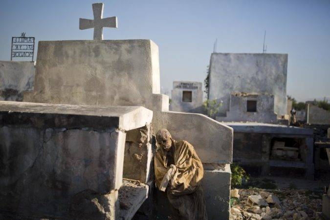 En esta imagen, tomada el 29 de marzo de 2017, los restos de un cuerpo exhumado descansan junto a su tumba antes de ser trasladado a una fosa común en el cementerio nacional de Puerto Príncipe, en Haití. Muchos haitianos se sumen en deudas de por vida para despedir a sus seres queridos fallecidos. Un funeral en Haití cuesta de media 5.000 dolares, muy por encima del salario anual de muchos. (AP Foto/Dieu Nalio Chery).