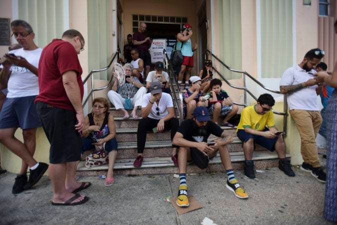 La gente se reúne en una zona donde hay internet el domingo 24 de septiembre de 2017 en San Juan, Puerto Rico, tras el paso del huracán María. (AP Foto/Carlos Giusti)