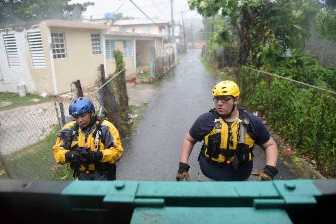 Julio Feliciano (left, and Adrian Colon, right, both rescue staff members from the Municipal Emergency Management Agency toured the streets of the Matelnillo community searching for citizens in distress during the passage of Hurricane Irma through the northeastern part of the island in Fajardo, Puerto Rico, Wednesday, Sept. 6, 2017. The US territory was first to declare a state of emergency las Monday, as the National Hurricane Center forecast that the storm would strike the Island Wednesday. (AP Photo/Carlos Giusti)