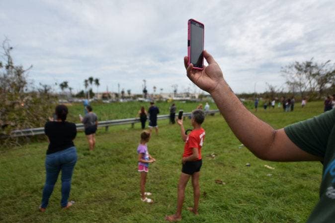 People try to get a cellphone signal in Dorado, 40 km north of San Juan, Puerto Rico, on September 23, 2017. Comunications, electric power, water supply and the lack of gas have been seriusly affected after the passage of Hurricane Maria. Puerto Rico Governor Ricardo Rossello called Maria the most devastating storm in a century after it destroyed the US territory's electricity and telecommunications infrastructure.
 / AFP / HECTOR RETAMAL