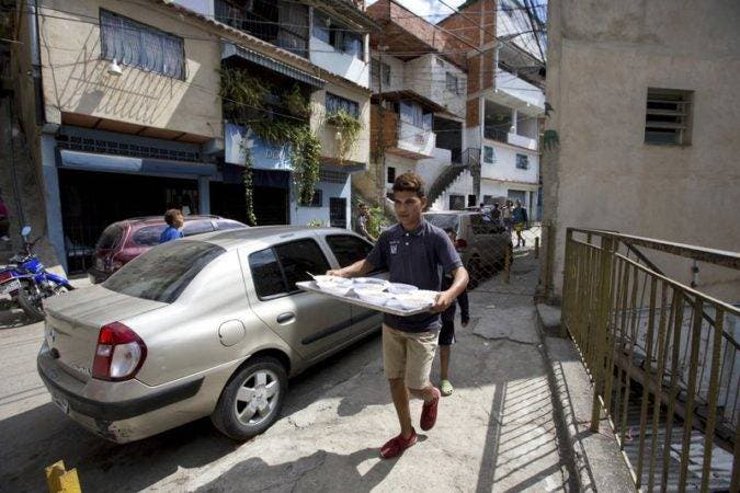  un voluntario lleva una bandeja de comida para servir a los vecinos en un comedor social impulsado por la oposición en Caracas, Venezuela. (AP Foto/Fernando Llano).