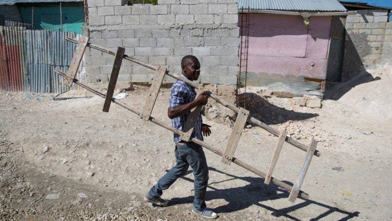 HAI01. PUERTO PRÍNCIPE (HAITÍ), 08/01/2020.- Jean Louis René camina este lunes, 6 de enero de 2020, en el campamento de refugiados Coral, en Croix Des Bouquets, Puerto Príncipe (Haití). Sin agua potable, bajo unos techos de zinc que no ofrecen protección de la lluvia y con unas fétidas letrinas comunitarias, miles de haitianos continúan malviviendo en los refugios temporales levantados hace diez años tras el sismo que devastó la región de Puerto Príncipe en 2010. EFE/ Orlando Barría