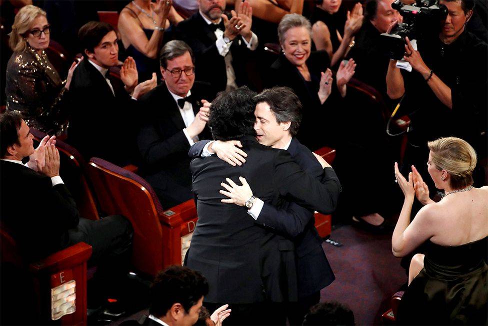 El director surcoreano Bong Joon-ho recibió un abrazo de su colega cineasta Noah Baumbach cuando fue anunciado como ganador del galardón de mejor guión original por "Parasite".