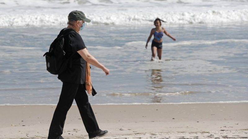 na mujer camina junto a la orilla en la playa Jones Bach, en Wantagh, Nueva York, el 21 de mayo del 2020. Los neoyorquinos ansiosos por dos meses de cuarentena por coronavirus recibieron un inesperado alivio cuando el gobernador Andrew Cuomo aflojó las restricciones a reuniones públicas en el estado para el feriado del Día de los Caídos en Guerras. (AP Foto/Kathy Willens)