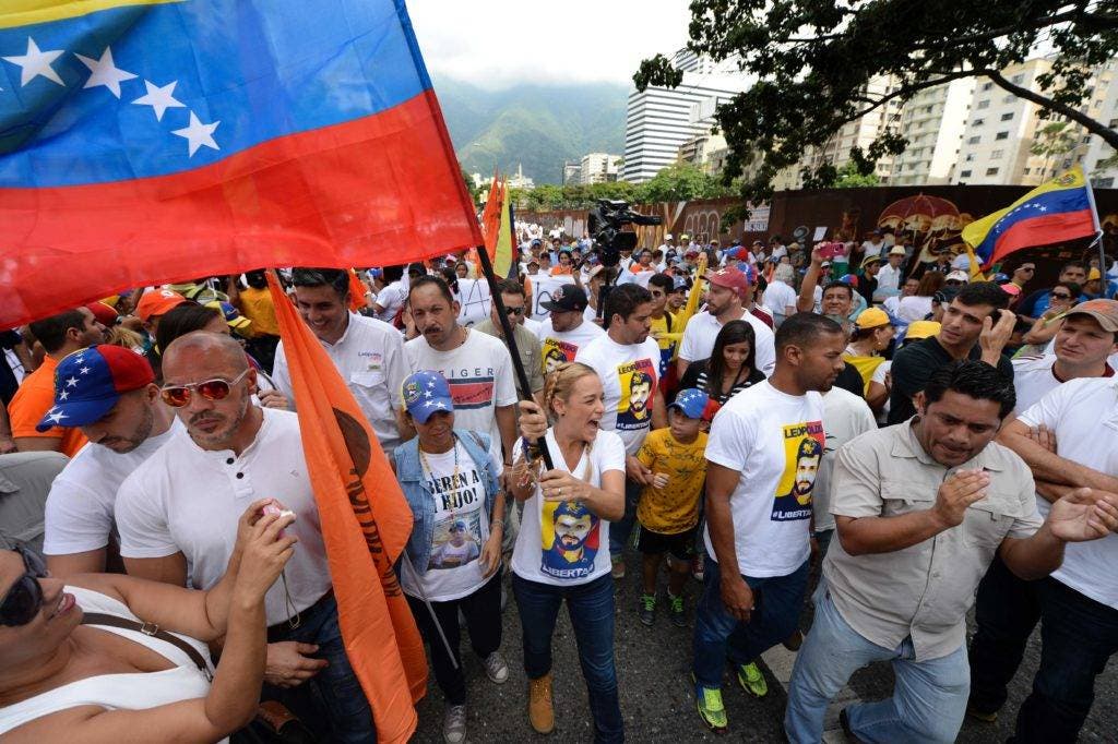 Lilian Tintori, wife of prominent jailed opposition leader Leopoldo Lopez, waves a Venezuelan national flag as she marches against the government of President Nicolas Maduro in the streets of Caracas on October 26, 2016.  Venezuela's political rivals are set to engage in a volatile test of strength on Wednesday, with the opposition vowing mass street protests as President Nicolas Maduro resists efforts to drive him from power. The socialist president and center-right-dominated opposition accuse each other of mounting a "coup" in a volatile country rich in oil but short of food. / AFP / Federico PARRA