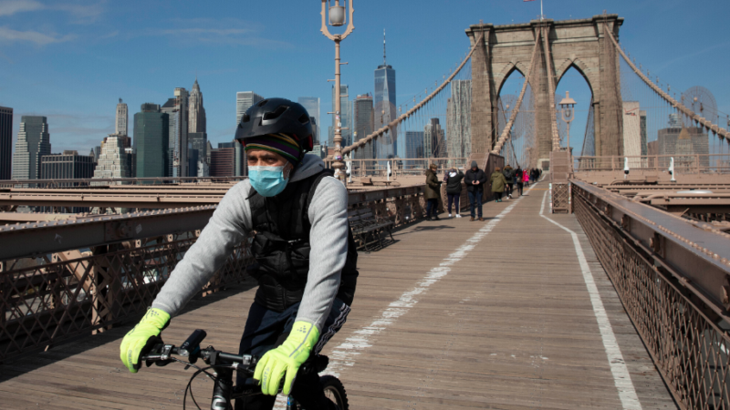 Un ciclista con mascarilla pa,ra prevenir coronavirus cruza el Puente de Brooklyn-AP