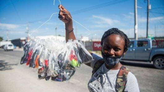 Una mujer vende mascarillas cerca de la entrada del Parque industrial, en el primer día en que su uso es obligatorio, este lunes en Puerto Príncipe. EFE