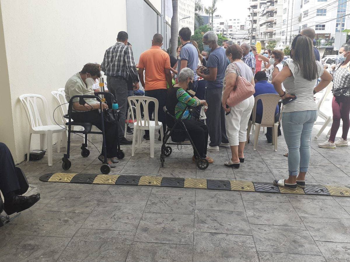 Ancianos en sillas de ruedas esperan debajo del sol vacunas anticovid