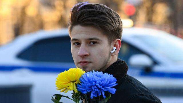 Un joven sostiene flores con los colores de la bandera ucraniana durante una protesta el 24 de febrero de 2022.