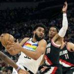 Karl-Anthony Towns, centro, hace ofensiva con el balón.