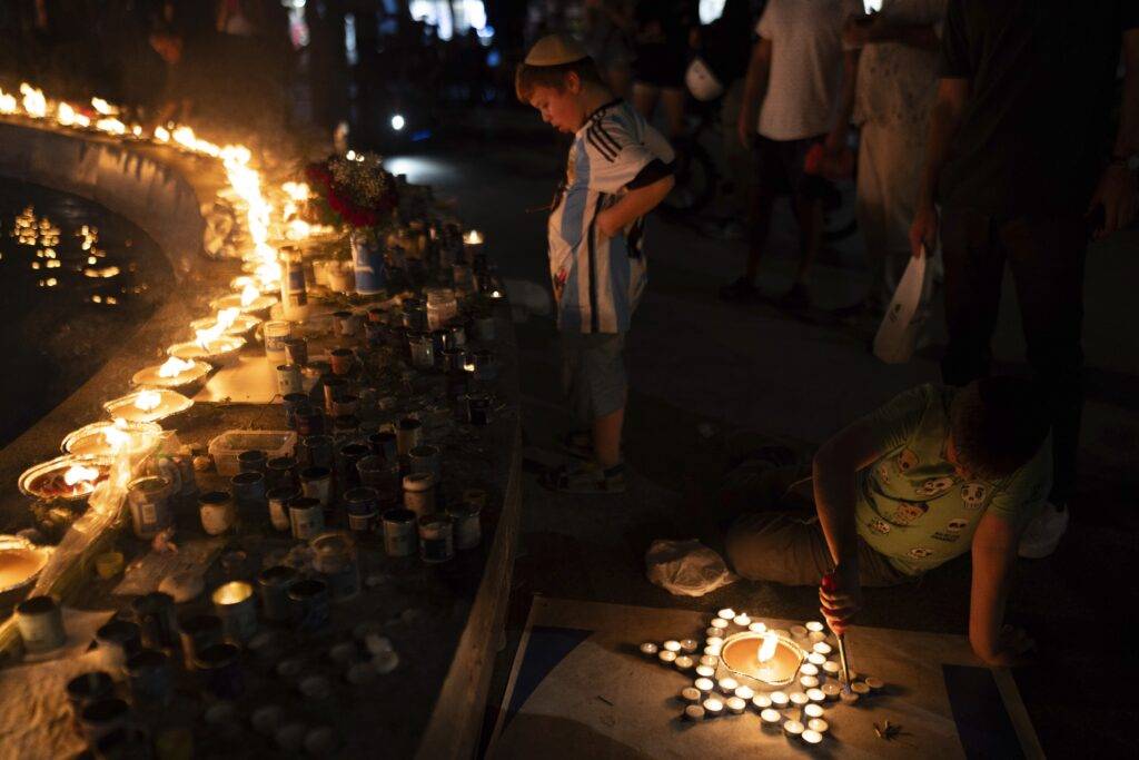 Un niño enciende velas que forman una estrella de David en honor a las víctimas de los ataques de Hamás, durante una vigilia en la plaza Dizengoff, en el centro de Tel Aviv, Israel, el 18 de octubre de 2023. (AP Foto/Petros Giannakouris)